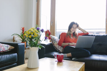 Young woman with laptop relaxing on the couch in her living room - BOYF000025