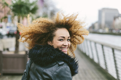 Ireland, Dublin, smiling woman with afro looking over her shoulder - BOYF000028