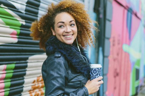 Porträt einer lächelnden Frau mit Kaffee zum Mitnehmen, lizenzfreies Stockfoto