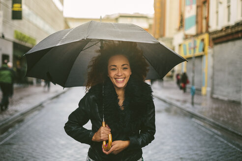 Porträt einer lächelnden Frau mit Regenschirm an einem regnerischen Tag - BOYF000045