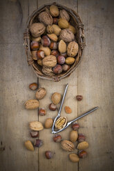 Wickerbasket, walnuts, almonds, hazelnuts and nutcracker on wood - LVF004260