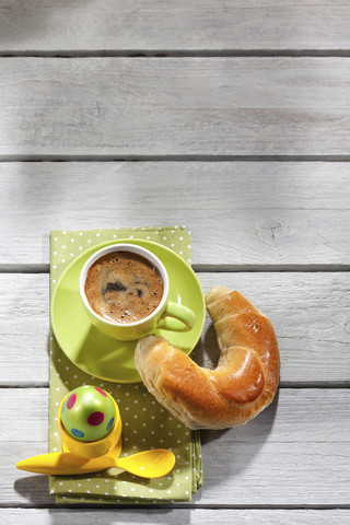 Frühstück mit gefärbtem Osterei, Tasse Kaffee und Gebäck, lizenzfreies Stockfoto