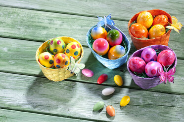 Four Easter nests with coloured Easter eggs on green wood - CSF026897