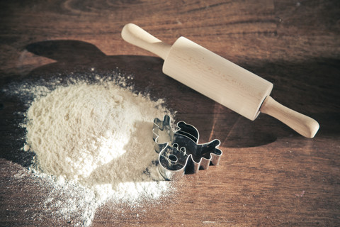 Mehl, Nudelholz und Ausstecher auf dunklem Holz, lizenzfreies Stockfoto