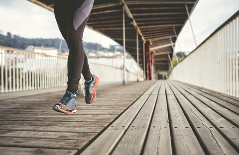 Spanien, Naron, Beine eines Joggers, der auf einer Holzbrücke läuft, lizenzfreies Stockfoto