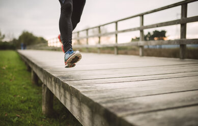 Spain, Naron, legs of a jogger running on a boardwalk - RAEF000698