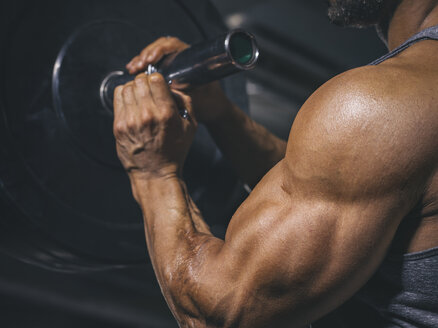 Bodybuilder bereitet eine Langhantel auf einem Power Rack im Fitnessstudio vor - MADF000762