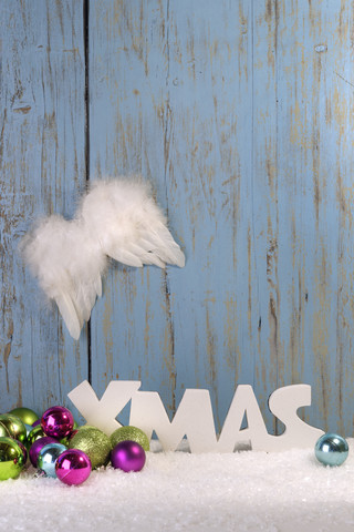 Weihnachtsdekoration mit Kugeln, Engelsflügeln und Kunstschnee vor einer Holzwand, lizenzfreies Stockfoto