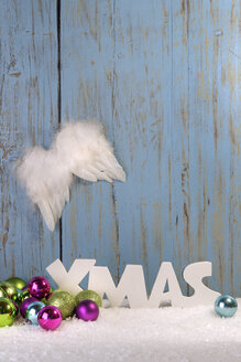 Weihnachtsdekoration mit Kugeln, Engelsflügeln und Kunstschnee vor einer Holzwand - LBF001306