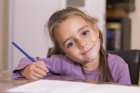 Portrait of smiling little girl with blue pencil stock photo