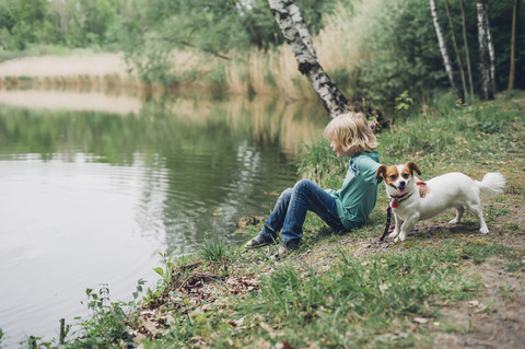 Germany, Saxony, boy with dog at the lakeside stock photo