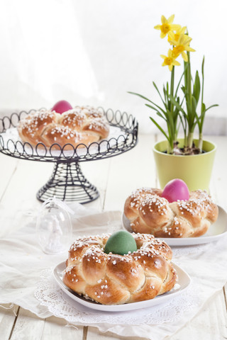 Geflochtenes Osterbrot mit bunten Eiern und Narzissen, lizenzfreies Stockfoto