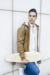 Teenager mit Longboard, das an einer Wand lehnt - ABZF000168