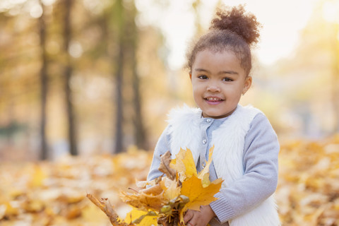 Kleines Mädchen spielt im Herbst im Park, lizenzfreies Stockfoto