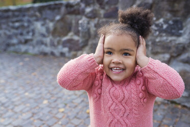 Little girl smiling, hands over ears - HAPF000020