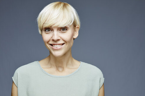 Porträt einer lächelnden blonden Frau vor einem grauen Hintergrund - RH001057