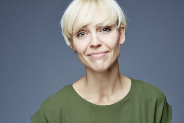 Porträt einer lächelnden blonden Frau vor einem grauen Hintergrund - RH001059