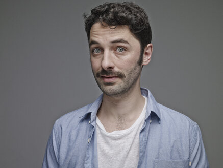 Portrait of sceptical man in front of grey background - RH001072