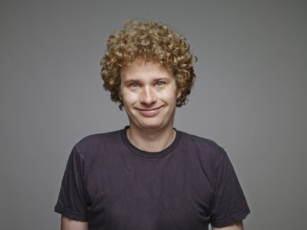 Portrait of smiling blond man in front of grey background - RH001076