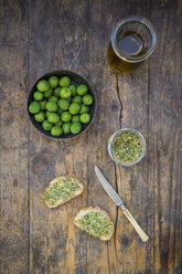 Bowl of green olives, carafe with olive oil, knife and slices of bread with olive spread - LVF004279