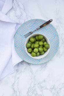Schale mit grünen Oliven auf Teller und weißem Marmor - LVF004289