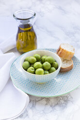 Bowl of green olives, slices of bread and carafe with olive oil - LVF004294