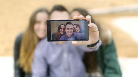 Selfie von lächelnden Freunden auf dem Display eines Smartphones, lizenzfreies Stockfoto
