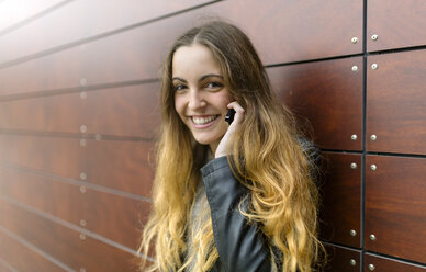 Portrait of smiling teenage girl on cell phone outdoors - MGOF001145