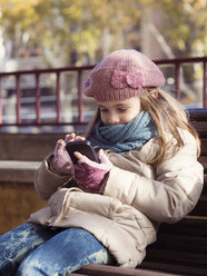 Mädchen in Winterkleidung spielt mit Smartphone - XCF000042