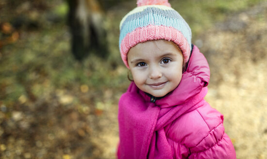 Portrait of smiling little girl wearing cap and scarf in autumn - MGOF001154