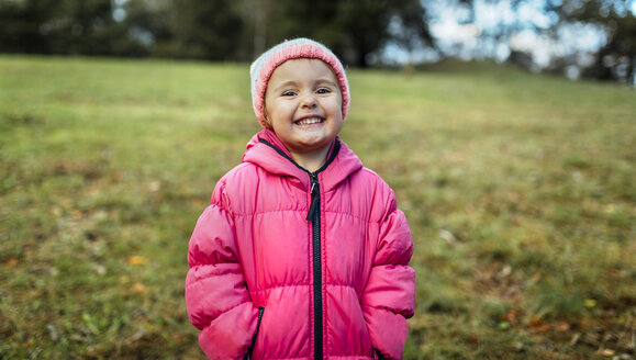 Portrait of smiling little girl wearing cap and pink jacket in autumn - MGOF001156