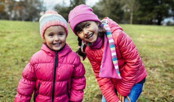 Porträt von zwei lächelnden kleinen Mädchen auf einer Wiese im Herbst - MGOF001157