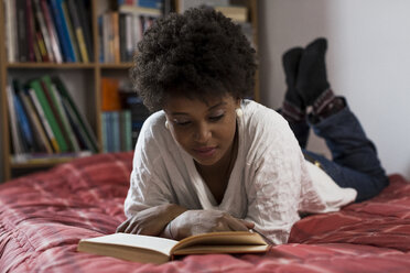 Junge Frau liegt zu Hause auf ihrem Bett und liest ein Buch - MAUF000142