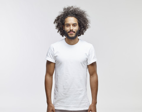 Porträt eines bärtigen jungen Mannes mit lockigem braunem Haar und weißem T-Shirt, lizenzfreies Stockfoto