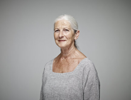 Portrait of smiling senior woman in front of grey background - RHF001107