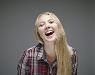 Porträt einer lachenden jungen Frau vor einem grauen Hintergrund - RHF001109