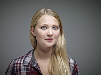 Portrait of young blond woman in front of grey background - RHF001110