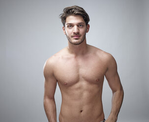 Porträt eines jungen Mannes ohne Hemd vor einem grauen Hintergrund - RHF001116