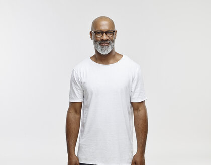 Porträt eines lächelnden Mannes mit Glatze und Bart, der eine Brille und ein weißes T-Shirt trägt - RHF001132