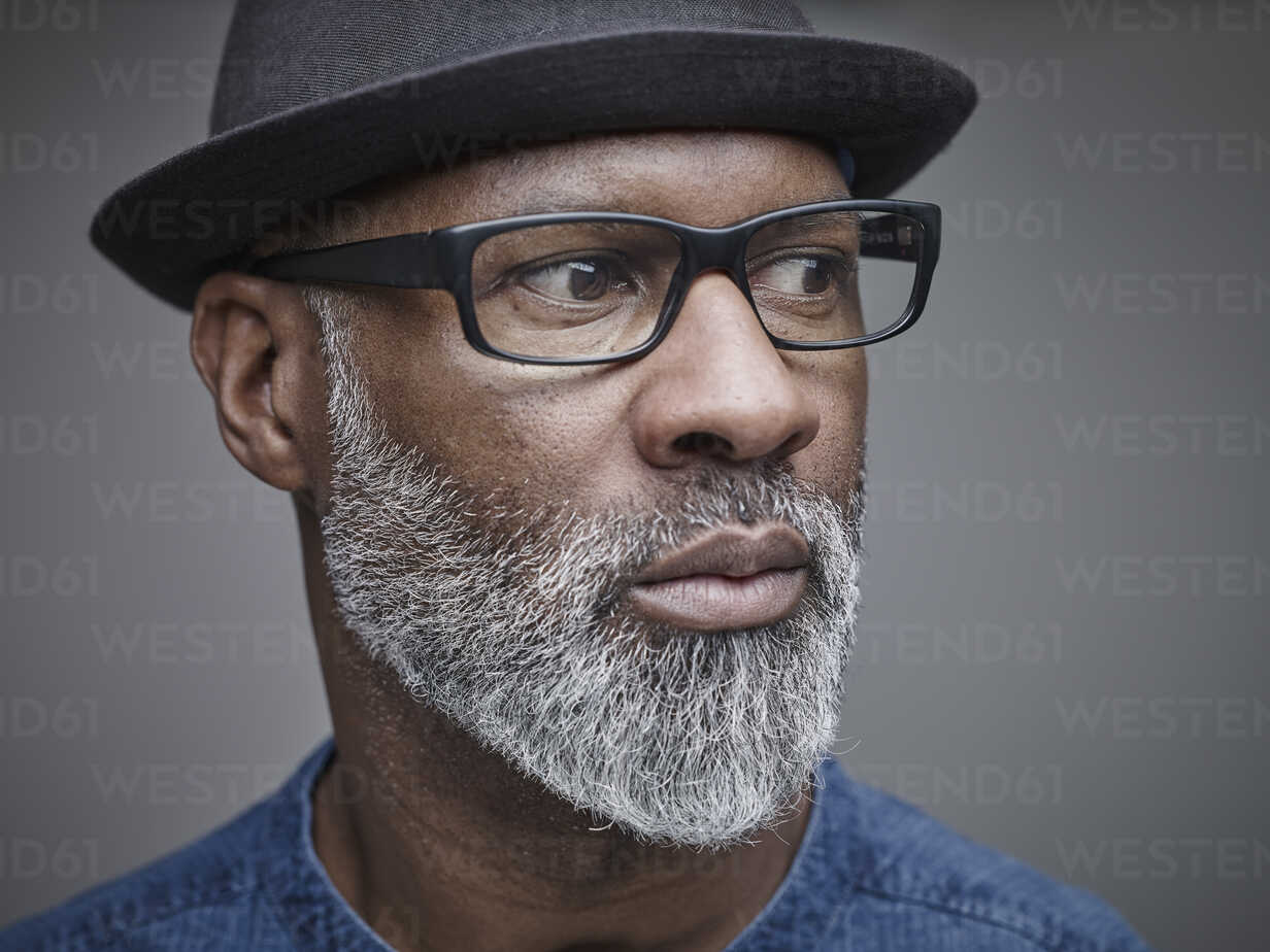 Portrait of man with grey beard wearing spectacles and hat stock photo