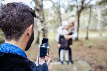 Father taking picture of wife and daughter in the forest - MGOF001165