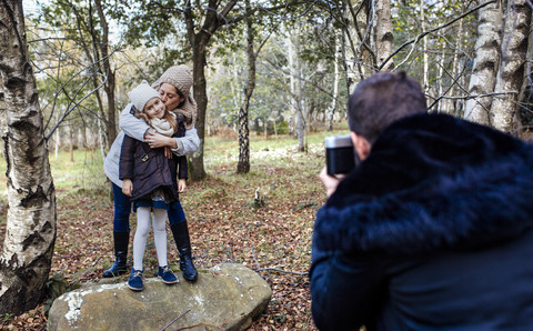 Father taking picture of wife and daughter in the forest stock photo