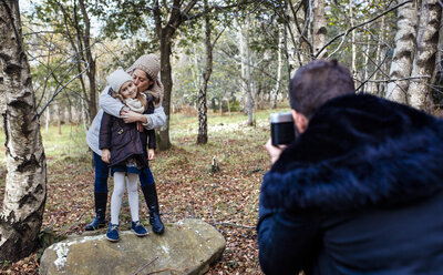 Father taking picture of wife and daughter in the forest - MGOF001166