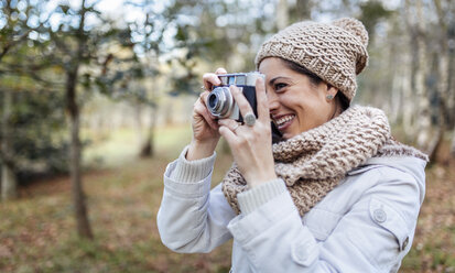 Glückliche Frau beim Fotografieren im Wald - MGOF001171