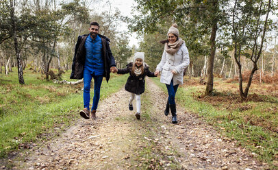 Happy parents with daughter walking on forest path - MGOF001173