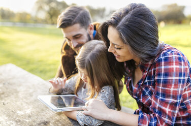 Glückliche Eltern mit Tochter, die im Freien ein digitales Tablet benutzt - MGOF001181