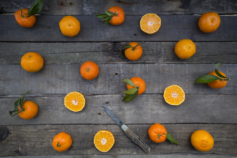 Ganze und geschnittene Mandarinen und ein Messer auf Holz, lizenzfreies Stockfoto