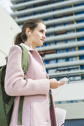 Junge Frau mit Ohrstöpseln und Mobiltelefon - UUF006171