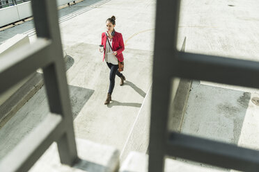 Junge Frau mit Coffee to go, Kopfhörern und Phablet auf dem Parkdeck - UUF006202