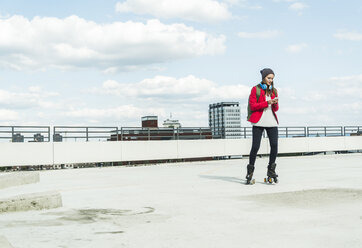 Young woman with cell phone and inline skates on parking level - UUF006205